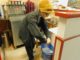 Junior Kay Harvey in a yellow beanie wringing materials out over a bucket of liquid while working at China Palace.